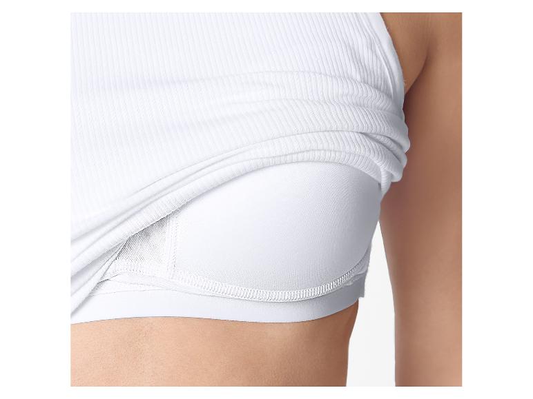 Nahaufnahme einer Frau in einem weißen gerippten Tanktop über einem weißen Sport-BH.
