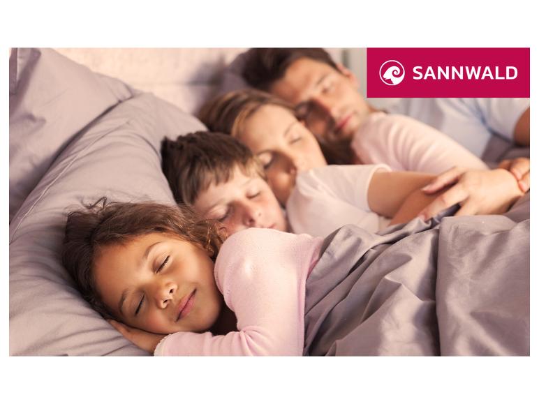 Familie schläft in einem Bett mit Sannwald Bettwäsche.