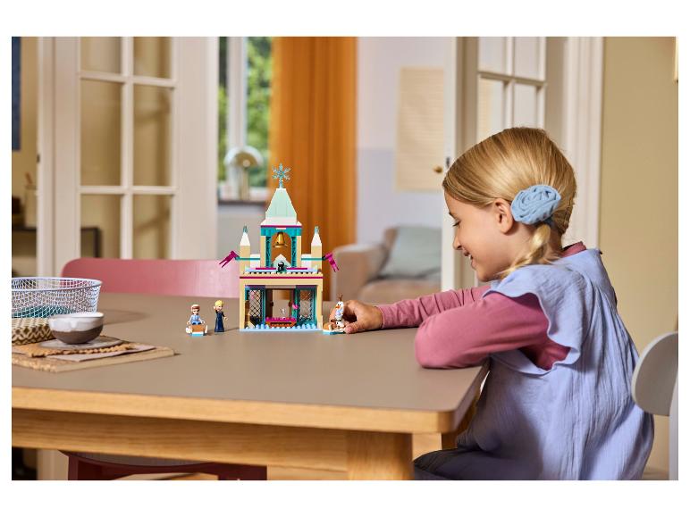 Lächelndes Mädchen spielt mit einem LEGO Disney Frozen Set.