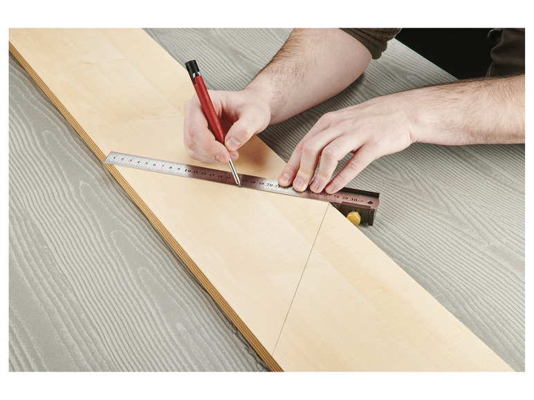 Eine Person benutzt ein Lineal und einen Bleistift, um eine Linie auf ein Stück Holz zu zeichnen.