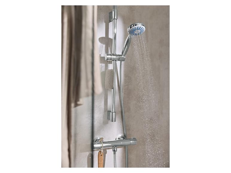 Ein Duschkopf mit spritzendem Wasser und einem Badeschwamm, der an der Stange hängt.