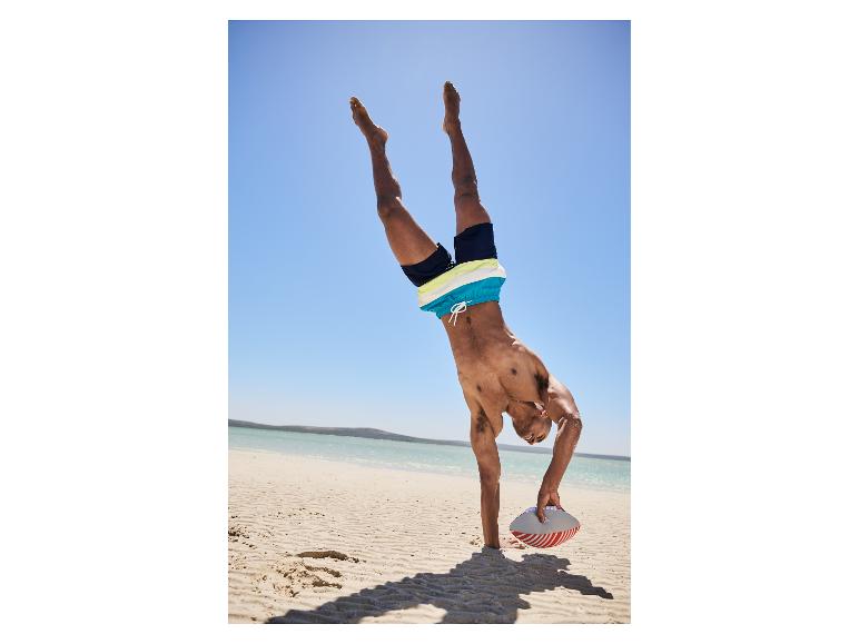 Badehose und Rugbyball am Strand.