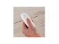Eine Hand hält eine weiße Fernbedienung mit einem Einschaltknopf auf einer Holzoberfläche.