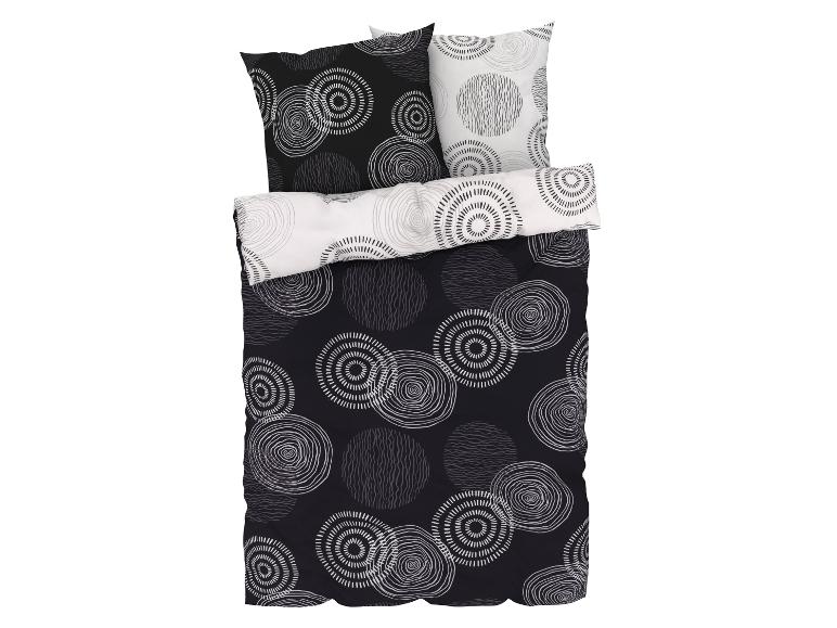 Ein schwarzer Bettbezug mit weißen Kreisen und zwei passenden Kissenbezügen.