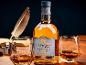 Flasche 'Winter's Gold' Whisky mit zwei Gläsern, Feder und Tinte auf Holzoberfläche.