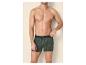 Oberkörperfreier Mann in grünen Boxershorts mit Palmenmuster.