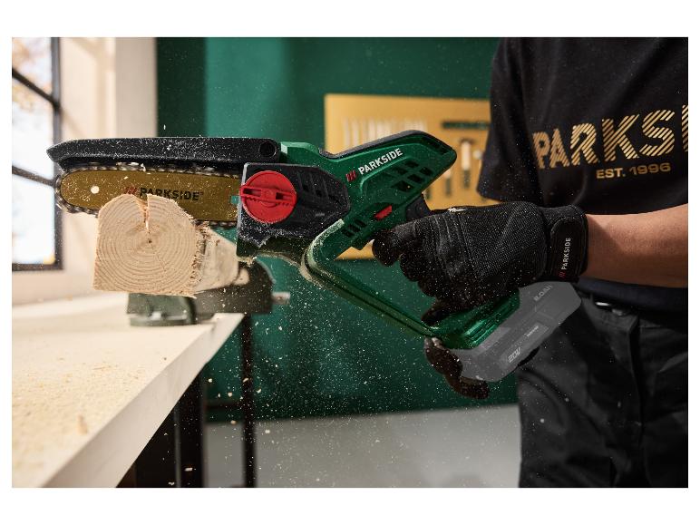 Akku-Mini-Kettensäge schneidet ein Stück Holz, mit fliegenden Holzspänen.