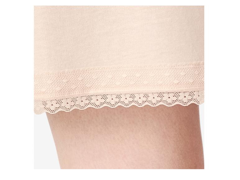 Nahaufnahme eines Frauenbeins in hellrosa Shorts mit Spitzenbesatz.