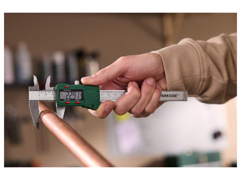 Eine Person misst ein Kupferrohr mit einem PARKSIDE Digitalmessschieber.