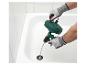 Mann mit Handschuhen benutzt einen manuellen Abflussreiniger in einer Badewanne.