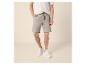 Mann in kurzärmeligem Strickhemd und Leinen-Shorts mit Kordelzug.