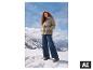 Frau in ESMARA® Premium Steppjacke und Jeans in verschneiten Bergen. [KI-generiertes Bild]