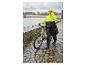 Frau im CRIVIT Premium-Regenponcho neben einem Fahrrad im Regen