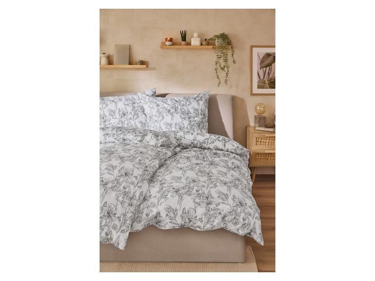 Bettwäsche mit Blumenmuster in einem Schlafzimmer mit Holzregalen und Dekorationen.