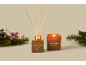 Duftdiffusor und Kerze mit Marshmallow Fireside Duft, umgeben von Tannenzweigen und Beeren.