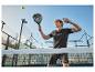 Mann in schwarzer Sportkleidung spielt Padel mit Schläger und Ball.