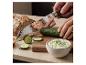 SILVERCREST® Premium-Küchenmesser schneidet eine Gurke auf einem Holzbrett neben Tzatziki und Brot.
