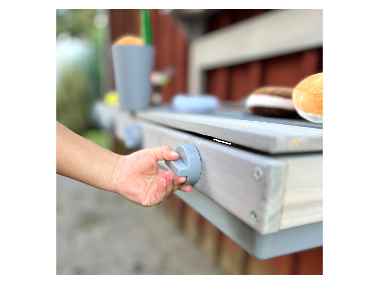 Ein Kind spielt mit einem grauen Holzspieltisch.