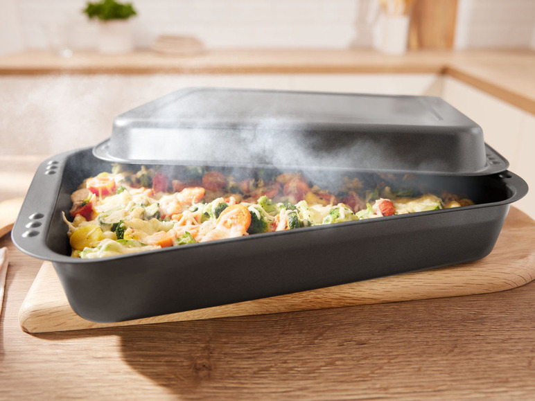 Eine Auflaufform mit gebackenem Gemüse und Käse, serviert auf einem Holzbrett.