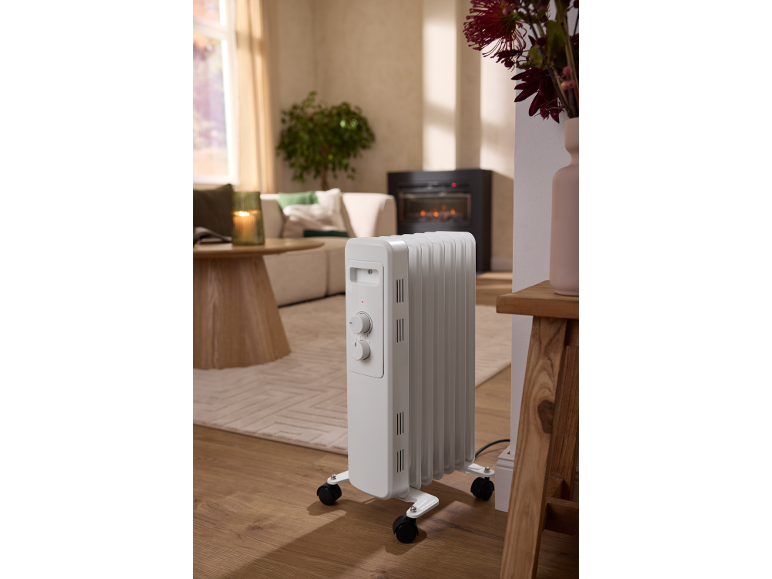 Tragbarer weißer Ölradiator in einem gemütlichen Wohnzimmer.