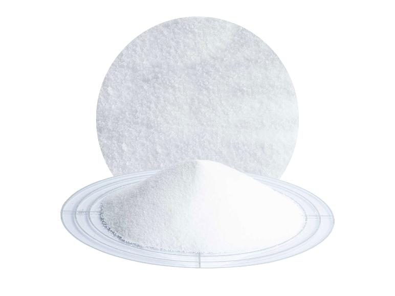 Weißes kristallines Pulver auf einem durchsichtigen Teller, mit vergrößerter Ansicht darüber.