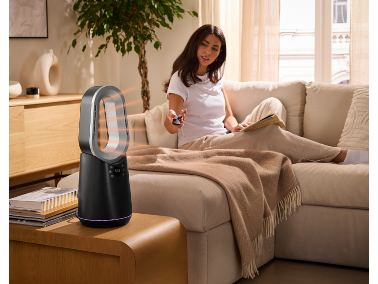 Tronic rotorloser Heizventilator auf einem Tisch im gemütlichen Wohnzimmer mit einer Frau auf dem Sofa.