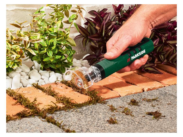 Mann entfernt Moos von Ziegelpflaster mit einer elektrischen Fugenbürste.