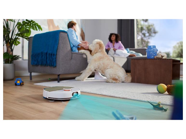 Saugroboter reinigt ein Wohnzimmer mit Menschen und einem Hund.