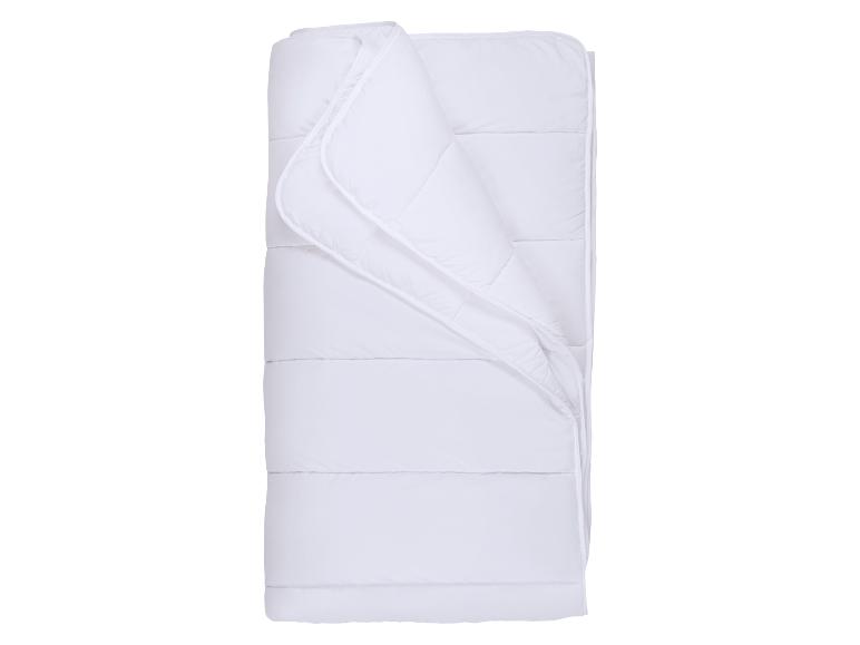 Weiße, gerollte Bettdecke mit gestepptem Muster.