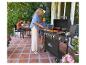 Familie grillt auf der Terrasse, Frau und Mädchen benutzen einen Gasgrill mit „GRILL MEISTER“.