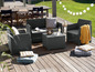 Eine graue Wicker-Lounge-Garnitur mit Couchtisch auf einer Holzterrasse.