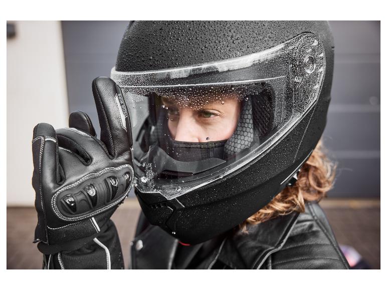 Person in schwarzem Motorradhelm mit Wassertropfen und schwarzem Handschuh mit 'VISOR WIPE' Text.