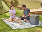 Eine Kühlbox, eine Picknickdecke und ein Paar, das sein Mittagessen im Freien genießt.