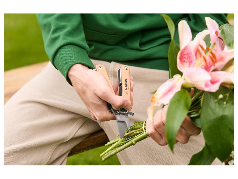 Person schneidet Lilienstiele mit einem Garten-Multifunktionswerkzeug.