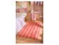 Schlafzimmer mit Zitronen-Bettwäsche, rosa Kissen und einem gestreiften orange-rosa Teppich.