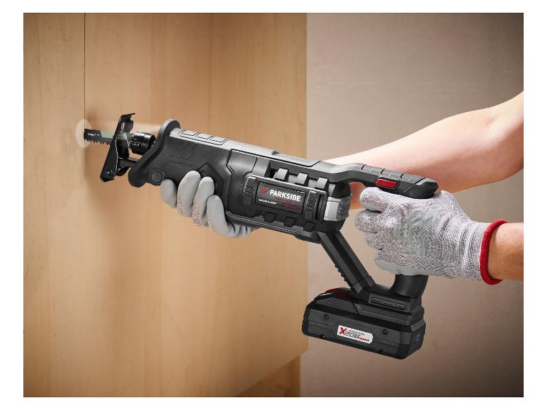 Eine Person benutzt eine Akku-Säbelsäge, um ein Loch in eine Holzwand zu schneiden.