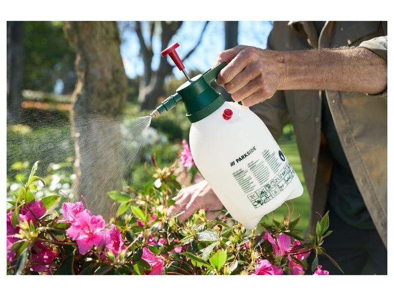 Mann besprüht rosa Blumen mit einer Parkside Sprühflasche