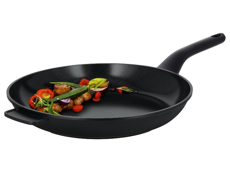 Schwarze Bratpfanne mit geröstetem Gemüse und Kräutern