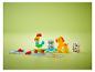 Bunte Bausteine mit Tierfiguren und einer Spielmatte auf grünem Hintergrund.