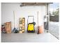 Gelbe Kehrmaschine in einer Garage mit Gartengeräten und Klapptisch.