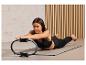 Eine Frau trainiert mit einem Pilatesring auf einer Matte.
