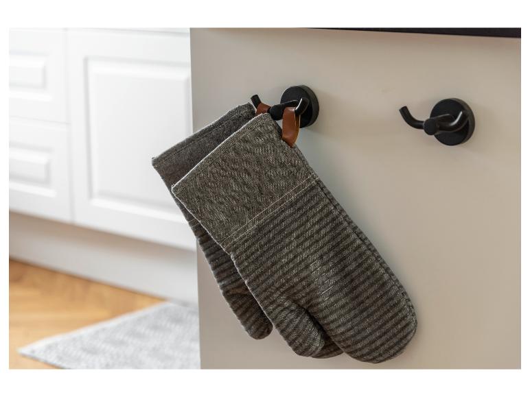 Zwei graue, gestreifte Topflappen hängen an einem Küchenhaken.