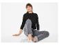 Frau in schwarzem Langarmshirt und grauer Jeans, auf dem Boden sitzend