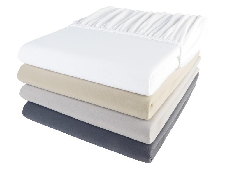 Ein Stapel von vier weißen, beigen, grauen und dunkelgrauen Spannbettlaken.