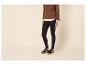 Frau in braunem Pullover, weißem Hemd, schwarzen Leggings und Sneakern.
