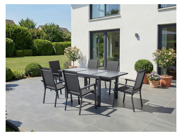 Gartenmöbel-Set mit grauem Tisch und Stühlen auf einer Terrasse, umgeben von Grün.