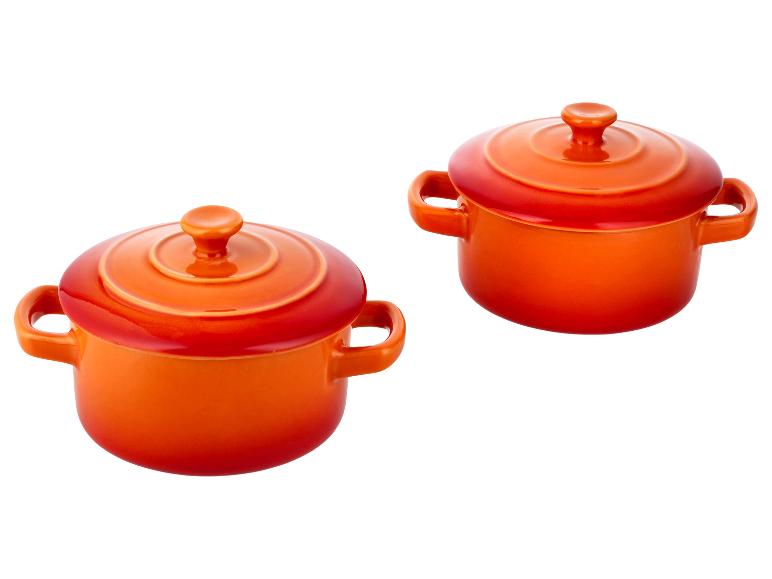 Zwei leuchtend orangefarbene Keramik-Auflaufformen mit Deckeln und Griffen.