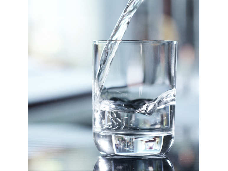 Transparentes Glas, das mit frischem, klarem Wasser gefüllt wird.