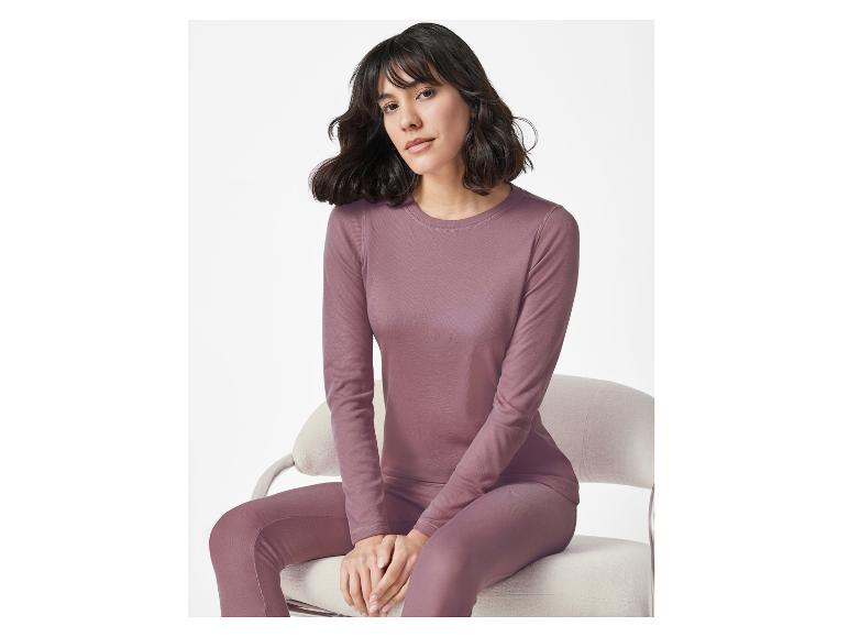 Frau sitzt auf Stuhl in lila Thermoshirt und Leggings.