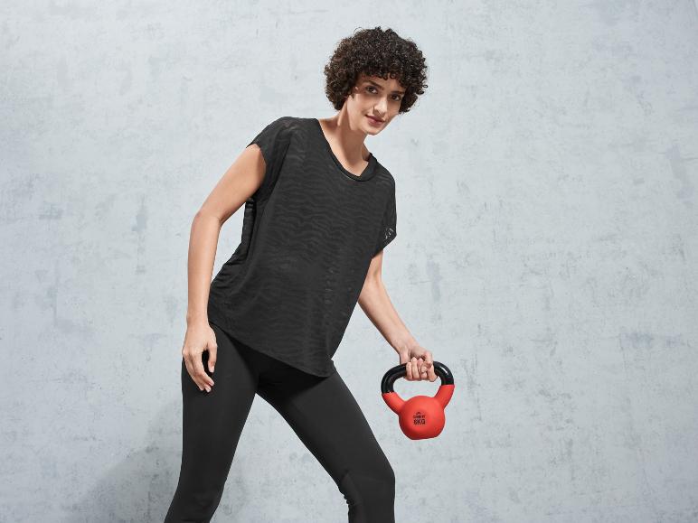 Eine Frau in schwarzen Leggings und einem Shirt hält rote Crivit-Hanteln.